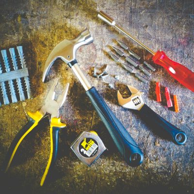 Collection of hand tools including hammer, screwdriver, and pliers in a workshop setting.